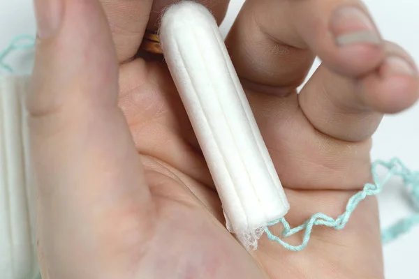 Tampão limpo branco na mão de mulheres isoladas em um fundo branco. Hora da menstruação. Higiene e protecção . — Fotografia de Stock