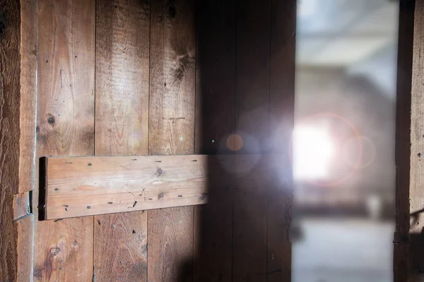 Alter hölzerner, dunkler Dachboden mit Sonnenlicht durch das Fenster und offener Tür, renovierungsbedürftig — Stockfoto