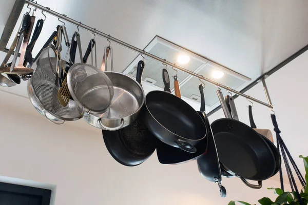 Stainless steel cookware , kitchenware set hanging on a rack on the wall, frying pans and saucepan in modern home — Stock Photo, Image