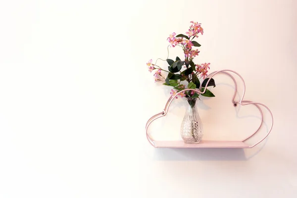 Dekoratives rosafarbenes Regal an weißer Wand mit Glasvase und rosafarbenen, leuchtenden Blumen, moderne, romantische Dekoration innen — Stockfoto