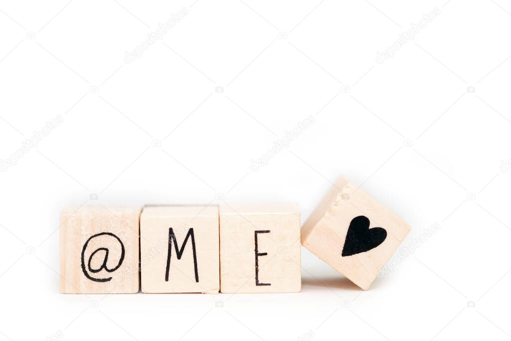 Wooden cubes with a At sign,the word Me and a heart symbol isolated on white background, self love concept