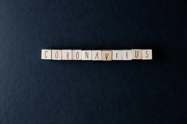 Coronavirus Épelé sur des cubes en bois avec des pilules médicales et des papiers de soie pour le virus Convid-19, vue du dessus fond noir — Photo