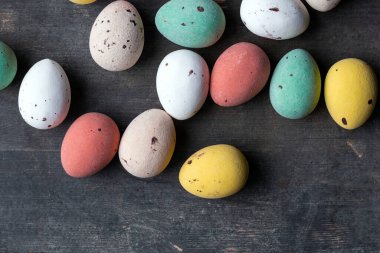 Eski ahşap arka plan dokusunda boyanmış renkli paskalya yumurtaları, yumuşak pasteller modern tasarım.