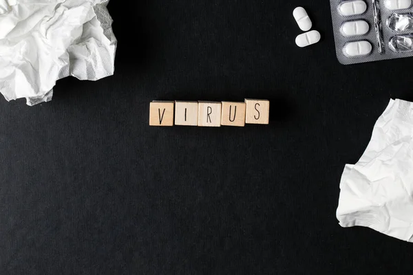 Cubi di legno con la parola Virus e pillole mediche, carte veline su sfondo nero vista dall'alto, concetto medico — Foto Stock