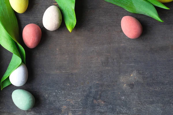 Ovos de páscoa coloridos tingidos em uma textura de fundo de madeira vintage, pastéis macios e folhas verdes design moderno — Fotografia de Stock
