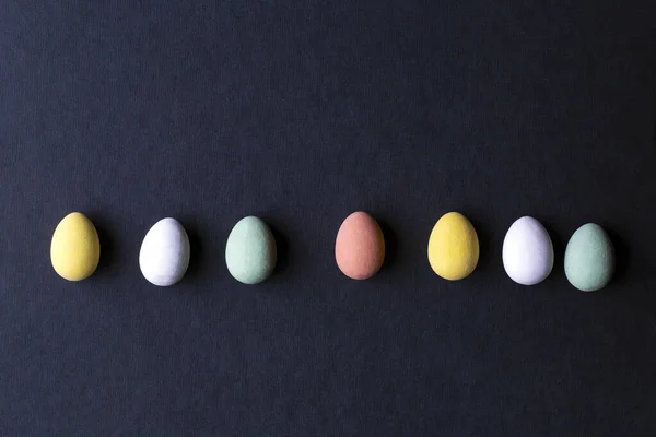 Huevos de Pascua pintados varios colores sobre fondo negro, vista superior diseño moderno — Foto de Stock