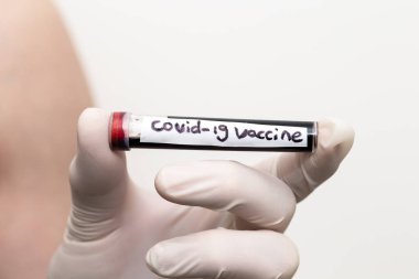 Kan tüpünde Covid-19 aşısı, tıbbi eldiven takmış bir doktor pozitif Coronavirus 2019 ncov kan örneğiyle dolu bir kan tüpü tutuyor..