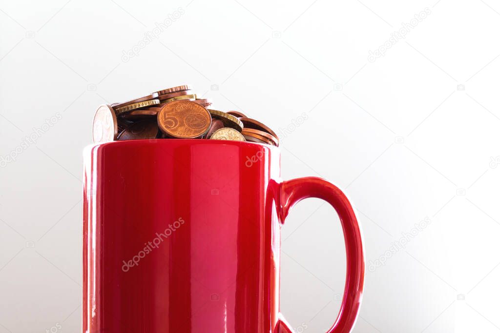 Saved Money in a colorful red mug to Finance Goals overflowing with euro coins, business concept