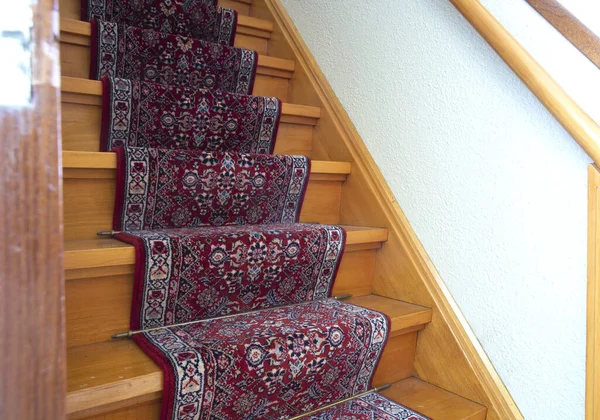 Stairs with red pattern carpet strip, old vintage wooden staircase, antique design