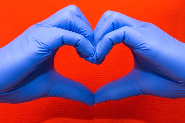 Sarung tangan lateks biru untuk perlindungan medis dalam bentuk hati simbol, mendukung dokter dan perawat, Covid-19, koronavirus. — Stok Foto
