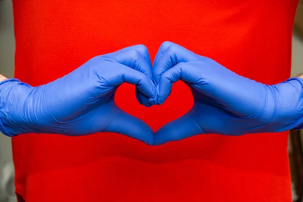 Sarung tangan lateks biru untuk perlindungan medis dalam bentuk hati simbol, mendukung dokter dan perawat, Covid-19, koronavirus. — Stok Foto