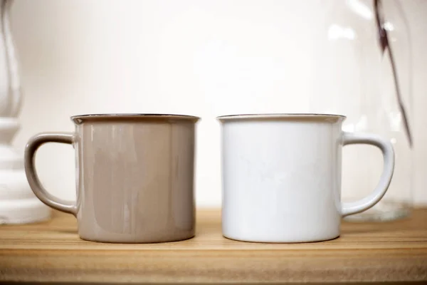 Kahverengi ve beyaz kahve fincanları ahşap masada, sevimli ev arka planında şirin bir tasarım. — Stok fotoğraf