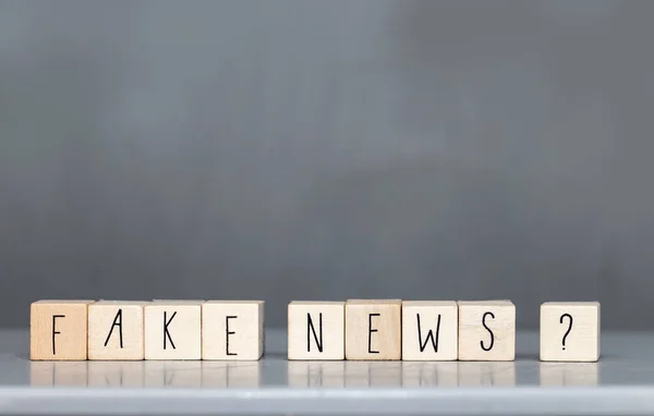 Cúpula de madera con las palabras Fake News sobre fondo gris, concepto de Fake News redes sociales — Foto de Stock