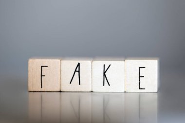 Gri arka plan, iş ve tasarım kavramında sahte sözcüğü olan tahta küp