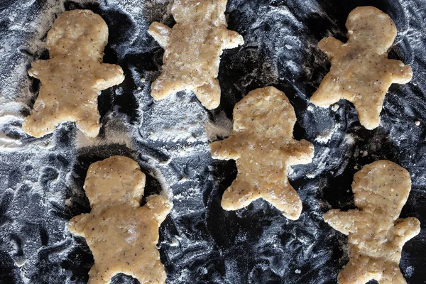 Személy sütés Mézeskalács ember cookie-k, Személy kéz a tészta virággal a hangulatos konyhában — Stock Fotó