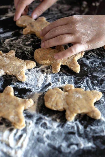Person baking Gingerbread man cookies, Person hands in dough with flower in cozy kitchen