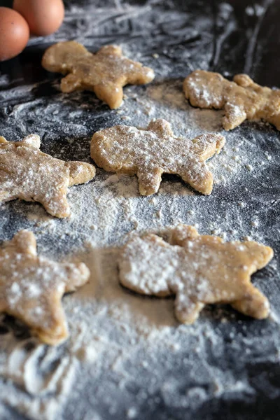 Person baking Gingerbread man cookies, Person hands in dough with flower in cozy kitchen