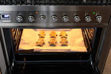 Fırında zencefilli ekmek pişiren adam, fırında ev yapımı zencefilli kurabiye yapan kadın.