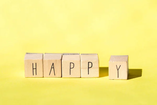Cubos de madeira com a palavra Feliz no fundo amarelo brilhante, conceito alegre — Fotografia de Stock