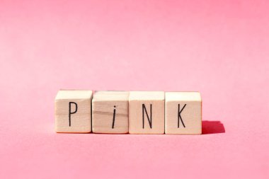 Ahşap küpler pembe arka planda pembe renkli pembe kavram sözcüğüyle sıralanır.