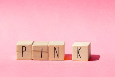 Ahşap küpler pembe arka planda pembe renkli pembe kavram sözcüğüyle sıralanır.