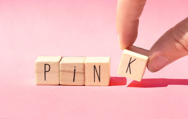 핑크라는 단어와 함께 분홍색 배경에 나무 조각들 이 한 줄로 놓여 있고 파스텔은 분홍색 자연적 인 개념을 가지고 있습니다. — 스톡 사진
