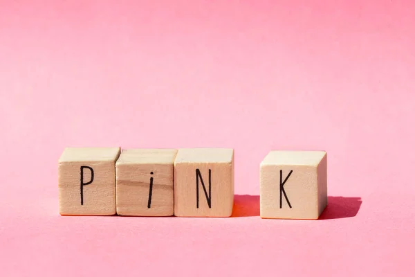 핑크라는 단어와 함께 분홍색 배경에 나무 조각들 이 한 줄로 놓여 있고 파스텔은 분홍색 자연적 인 개념을 가지고 있습니다. — 스톡 사진