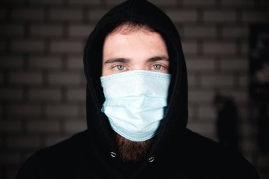 Covid-19 Coronavirus konsepti için tıbbi koruyucu yüz maskesi takan genç adamın portresi. Sağlığınızı koruyun. yakın plan