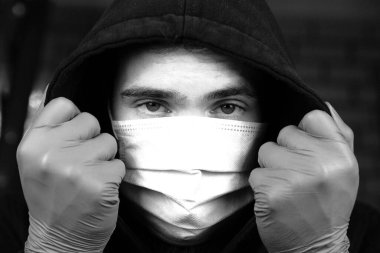Covid-19 Coronavirus konsepti için tıbbi koruyucu yüz maskesi takan genç adamın portresi. Sağlığınızı koruyun. Siyah beyaz yakın plan.