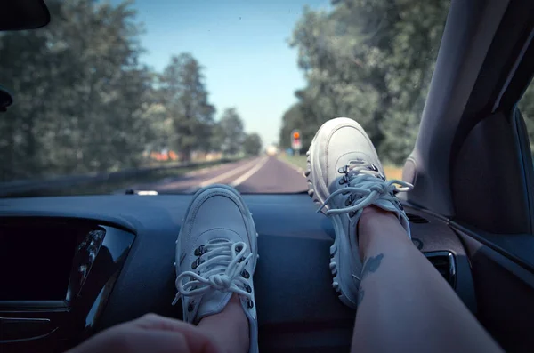 Vrijheid auto reizen concept - vrouw ontspannen met voeten op het dashboard het dragen van witte sneakers. Sexy vrouw in de auto. — Stockfoto