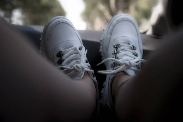 Freedom car travel concept - woman relaxing with feet on dashboard wearing white sneakers. Sexy woman in the car.