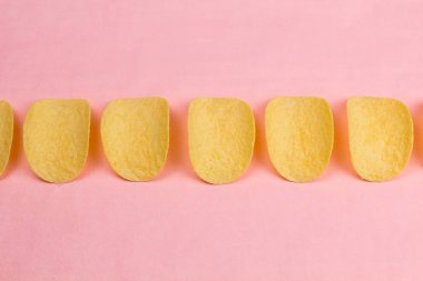 Patates cipsi minimalizm tarzı pastel pembe arka plan üzerinde.