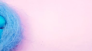 Paskalya yumurtaları güzel yuvaya pastel pembe bir arka plan üzerinde renkli.