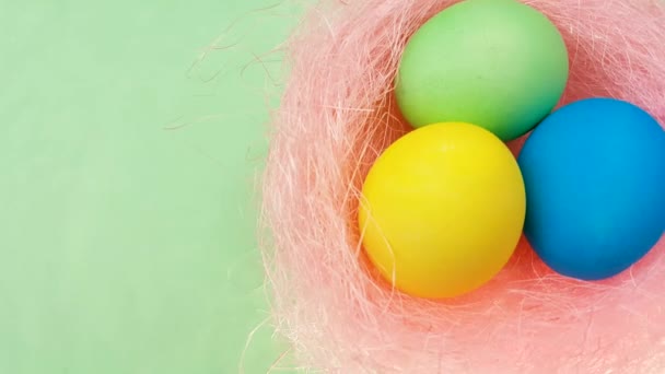 彩色复活节彩蛋在粉红色柔和的巢在绿色背景 — 图库视频影像