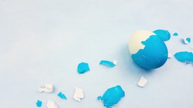 Pastel mavi arka plan üzerinde renkli Paskalya yumurta ile yumurta kabuğu.