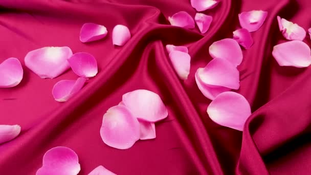 rosa Rosenblätter auf roter Seide in Nahaufnahme.