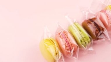 Renk tatlı macaroons veya şeffaf paket pastel pembe bir arka plan üzerinde macaron.