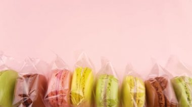 Renk tatlı macaroons veya şeffaf paket pastel pembe bir arka plan üzerinde macaron.