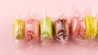 Renk tatlı macaroons veya şeffaf paket pastel pembe bir arka plan üzerinde macaron.