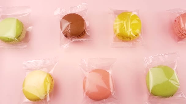 甘いマカロンの色やパステル ピンク背景の透明パッケージのマカロン — ストック動画