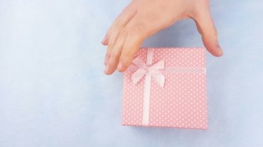 Kadın el macaroons veya pastel mavi zemin üzerine içinde macaron pembe kutusunu aç.