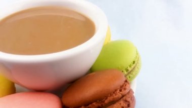 Bademli kurabiye veya pastel pembe yüzeyi beyaz fincan kahveyle macaron.