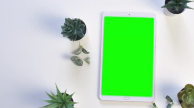 Yeşil çiçekli yeşil ekranlı beyaz tablet. Üst Manzara. 4k görüntü.