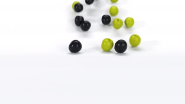 白い表面に転がる多くの緑と黒のオリーブ 新鮮な3D現実的な野菜の落下やロールの閉じます 4Kレンダリングアニメーション映像 — ストック動画