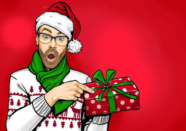 Amazed bearded man in glasses  and Santa hat with open mouth showing gift box. Emotions and advertisement. Surprised men. Christmas