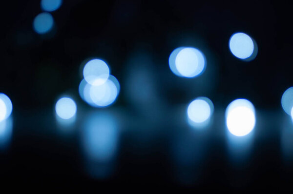 Beautiful white and blue bokeh on a dark background shot on the street at night