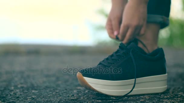 Ein junges Mädchen schnürt ihre Schnürsenkel an Turnschuhen. — Stockvideo