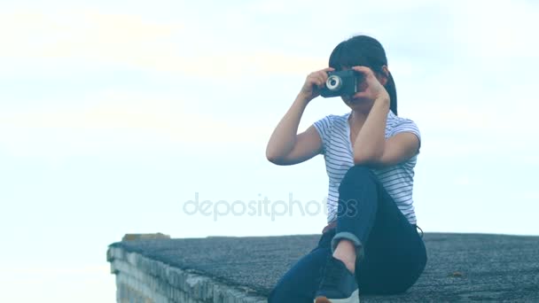 Брюнетка сидит на крыше дома — стоковое видео