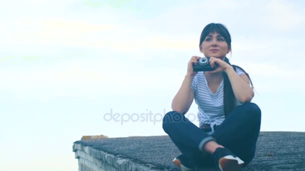 Брюнетка сидит на крыше дома — стоковое видео