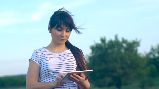 Chica morena escribe mensaje en una tableta — Vídeo de stock